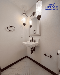 Stylish vintage bathroom with wall-mounted sink, elegant chandelier lighting, and black fixtures, highlighting expert home renovation services provided by Days Home Solutions. Beautiful vintage-style bathroom featuring a small wall-mounted sink, elegant black fixtures, a mirror, and decorative pendant lighting, showcasing home renovation and interior design by Days Home Solutions.