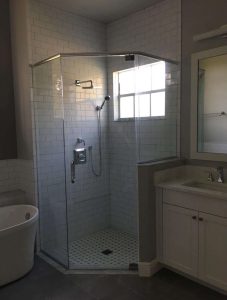 Contemporary bathroom with a glass shower enclosure, white subway tile walls, a vanity with a mirror, and natural lighting, showcasing home renovation and remodeling solutions. Modern bathroom with glass-enclosed shower, white subway tiles, and natural light from a large window. Features include a sleek vanity with a mirror and contemporary fixtures.