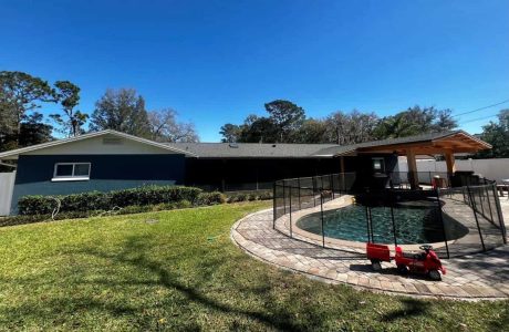 Beautiful backyard featuring a secure pool enclosure, landscaped lawn, and outdoor patio, ideal for enhancing home value and backyard living experience. Modern backyard with a safety pool fence, patio area, and a children's ride-on toy in front of a single-story house, showcasing home improvement and outdoor living solutions.