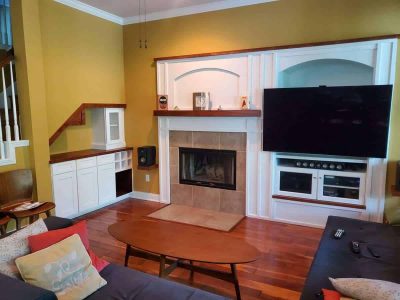 Spacious home entertainment area featuring a fireplace, large flat-screen TV, built-in storage, and stylish decor for comfortable family time. Modern living room with cozy fireplace, flat-screen TV, built-in cabinetry, and warm yellow walls, perfect for home entertainment and relaxation.