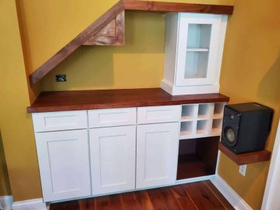 Custom home entertainment storage with white cabinets, wood accents, and open shelving for audio and media devices. Modern built-in custom entertainment center with white cabinetry, wood accents, and open shelving for audio equipment, perfect for home theater setup.