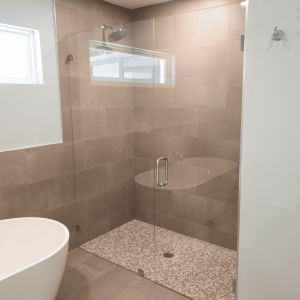 Luxury bathroom shower with contemporary design, frameless glass door, and tiled walls offering a sleek, modern look. Modern walk-in shower with glass enclosure and beige tile accents, perfect for upscale bathroom renovations.