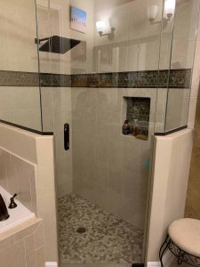 Elegant bathroom shower featuring beige ceramic tiles, a mosaic accent strip, and a sleek black showerhead for a contemporary look. Luxurious walk-in shower with frameless glass enclosure, modern tile design, and built-in niche for toiletries, perfect for upscale bathroom remodeling and home improvements.