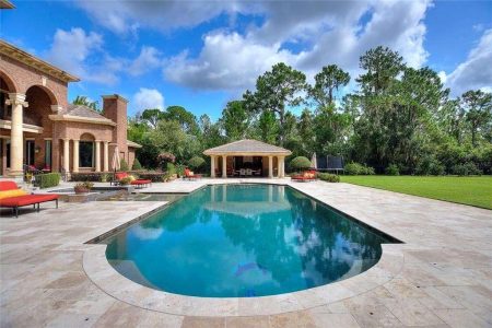 Beautiful backyard with swimming pool, outdoor lounge area, shaded pavilion, and landscaped garden, ideal for outdoor gatherings, relaxation, and enhancing home value. Luxurious backyard with a custom in-ground swimming pool, spacious patio, and elegant outdoor living space featuring lush landscaping and a shaded gazebo area for relaxing and entertaining.